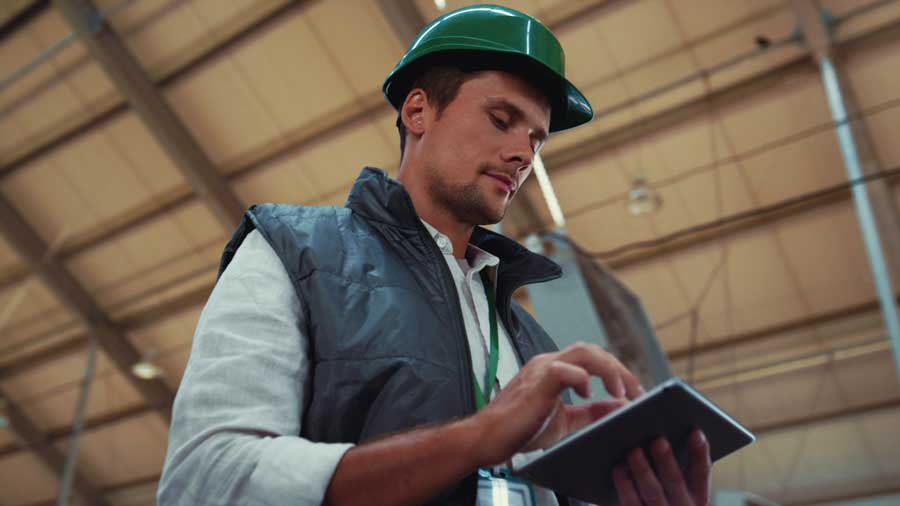 A business owner in a hard hat on location, reviews data from fleet fuel cards in real-time.