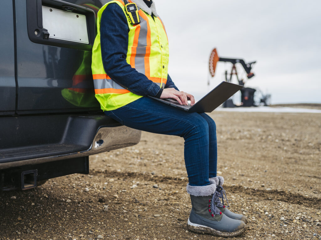 A fleet owner reviews fuel card usage on her laptop while at a construction site.