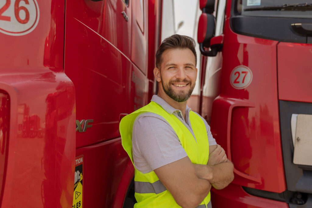 A truck driver in Canada smiles near his fleet.