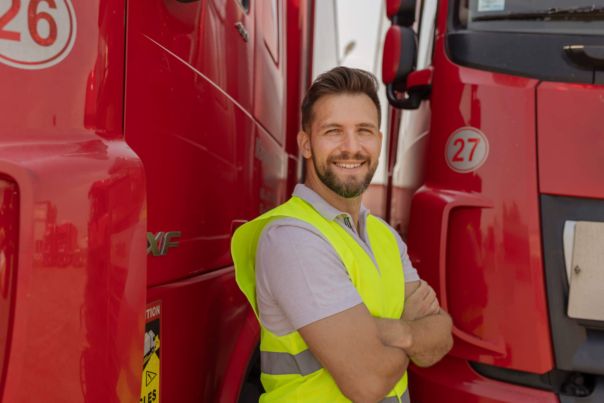 A truck driver in Canada smiles near his fleet.