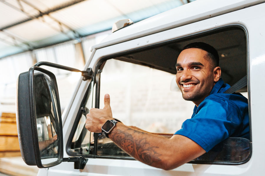 A fleet driver gives a thumb’s up from his semi truck cab.