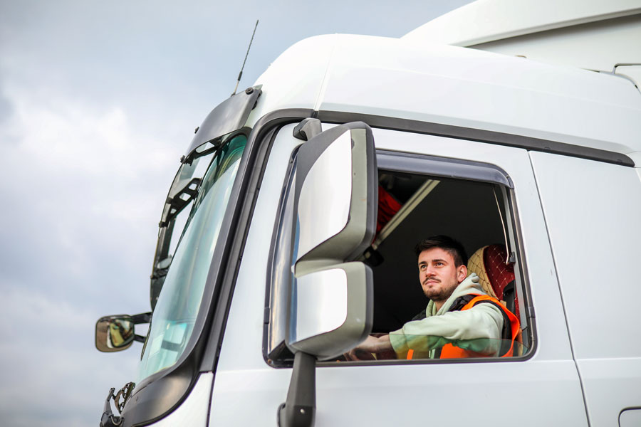 A truck driver in Canada sits in the cab of his semi truck on his route.