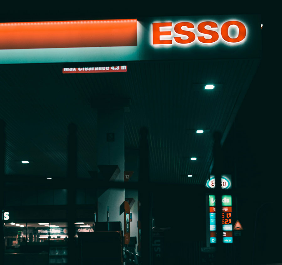 An Esso petrol station lit up at night.